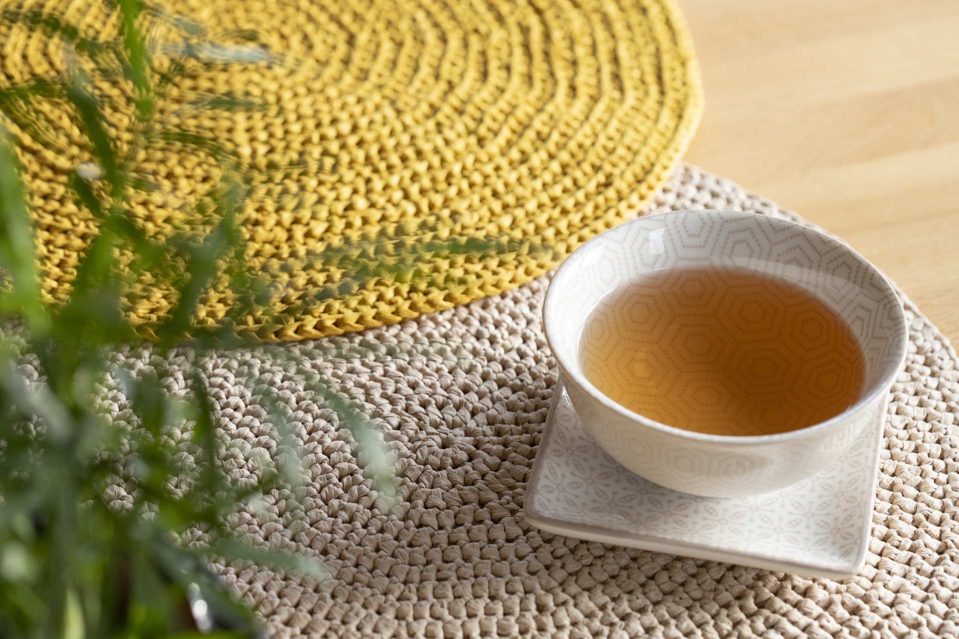 Xícara de chá branca com padrão hexagonal e tapete trançado bege