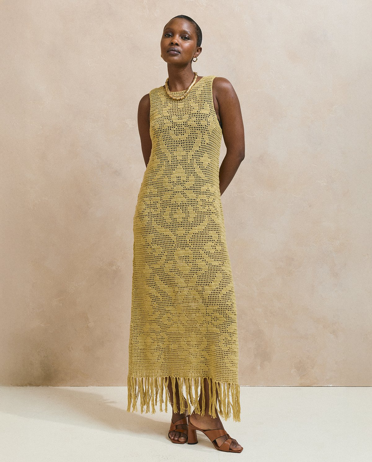 Vestido amarelo mostarda de malha com franjas na barra e padrão floral em renda.