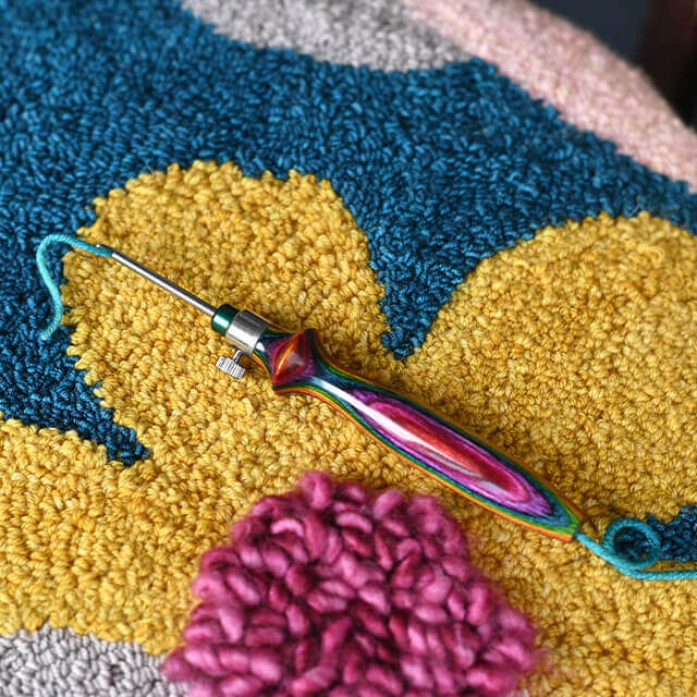 Gancho de crochet colorido sobre tapete felpudo com padrões coloridos