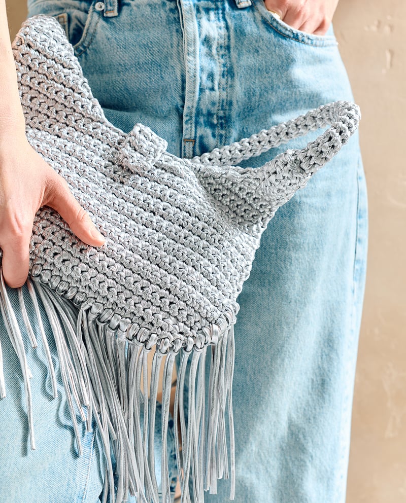 Bolsa trançada prateada com franjas em calças de ganga