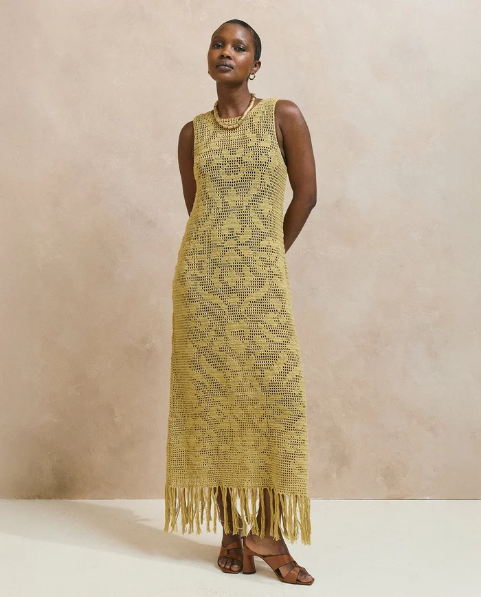 Modelo a usar vestido amarelo mostarda de malha com padrão e franjas
