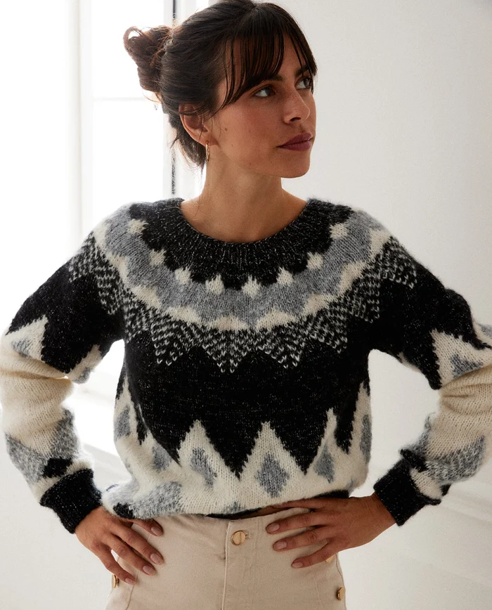 Mulher com camisola de lã preta, cinzenta e branca com padrão geométrico