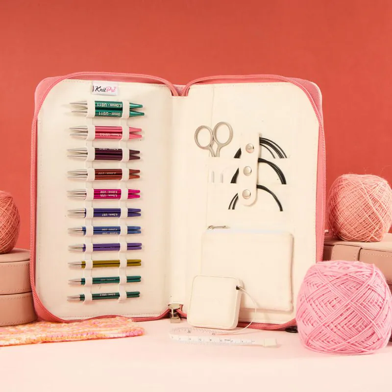 Conjunto de agulhas de tricô coloridas num estojo aberto com acessórios e novelos de lã rosa