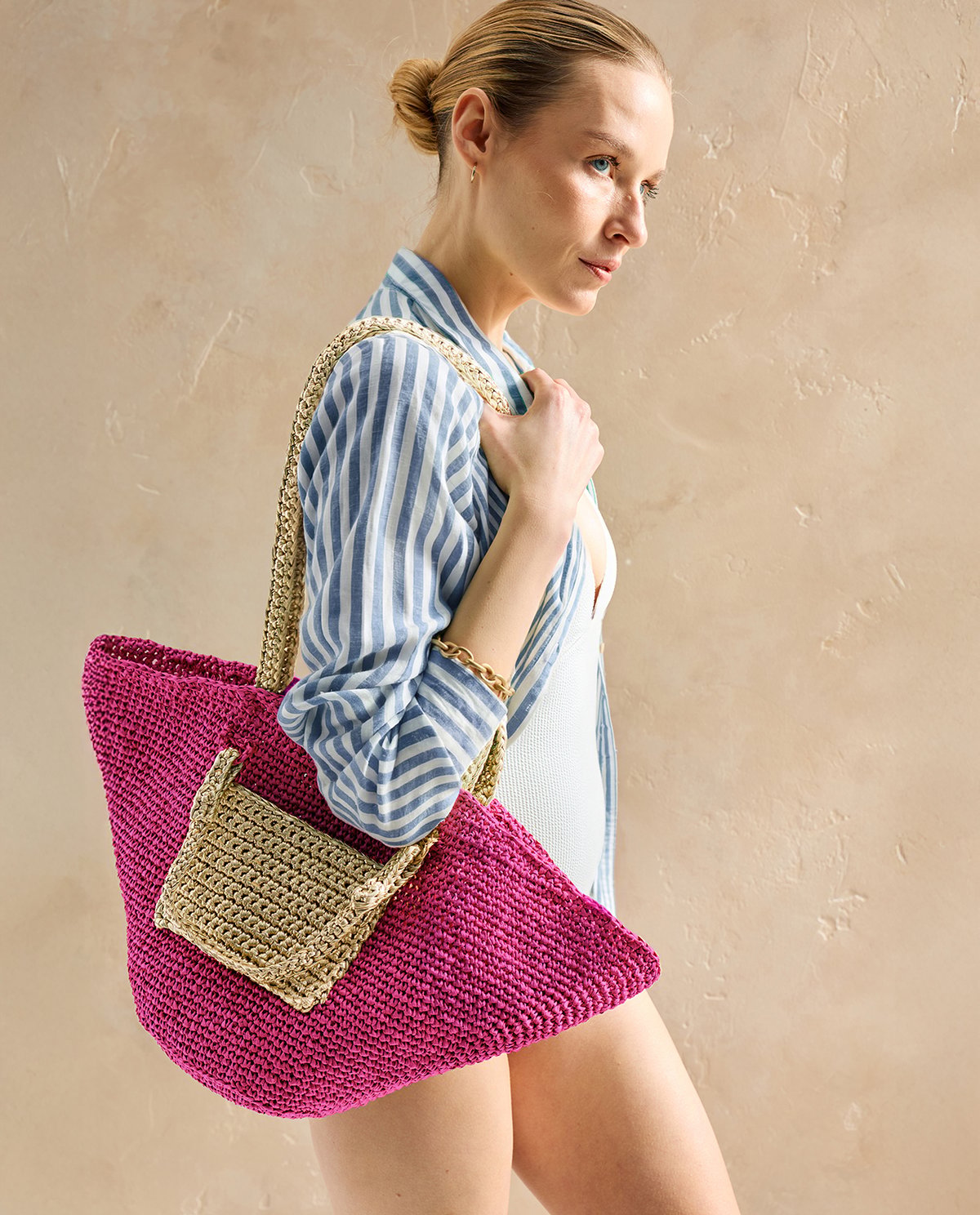 Mulher segurando mala grande cor-de-rosa trançada com bolso bege