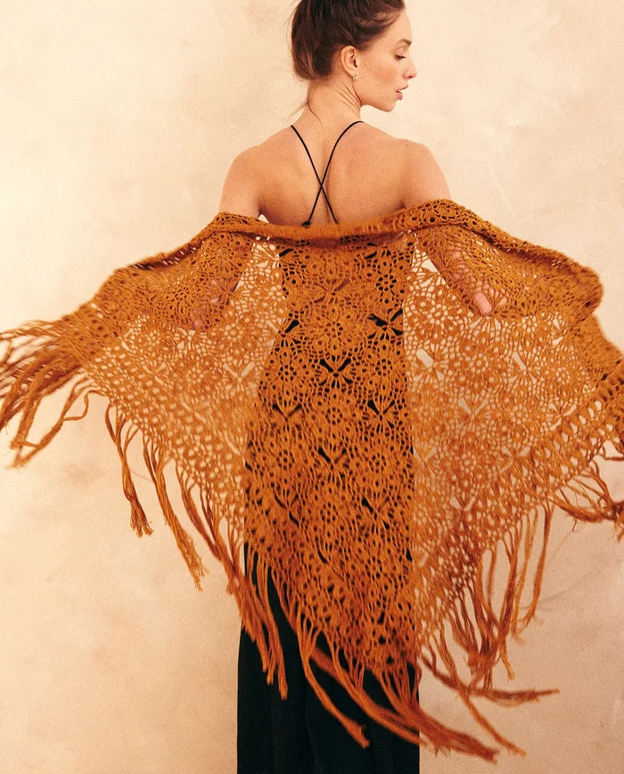 Mulher com xale de croché castanho alaranjado e vestido preto