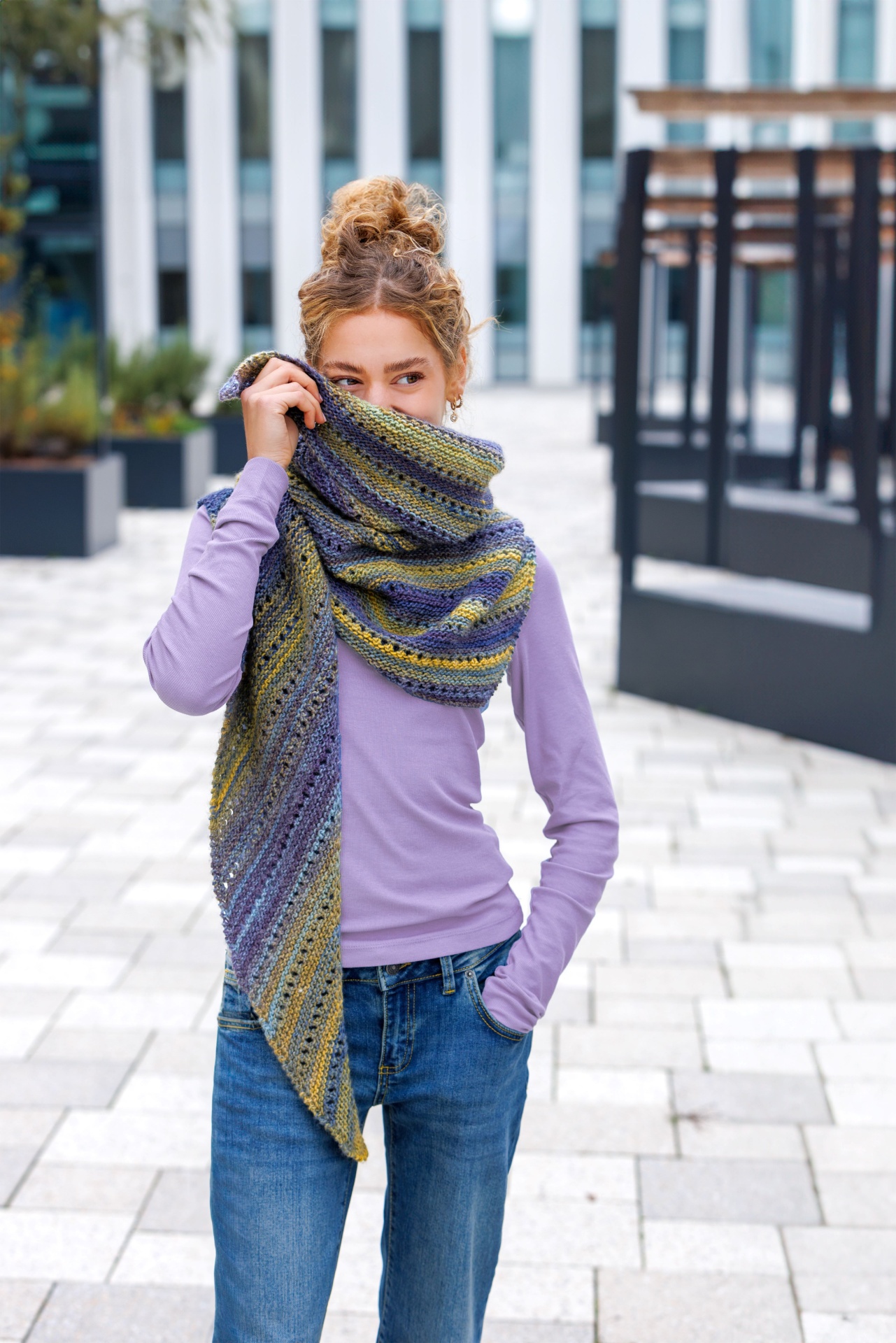 Mulher com cachecol tricotado colorido e camisola lilás ao ar livre