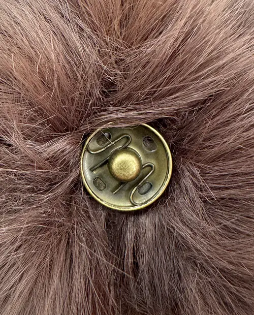 Close-up de botão metálico dourado em tecido peludo castanho claro