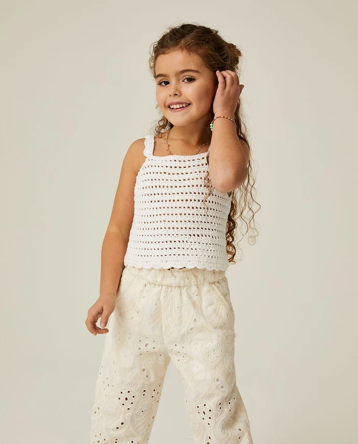 Menina de vestido branco com blusa crochet e calças bordadas