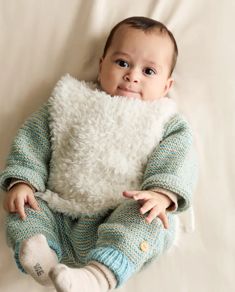 Bebé com roupa de malha às riscas azul e bege e babete branco felpudo