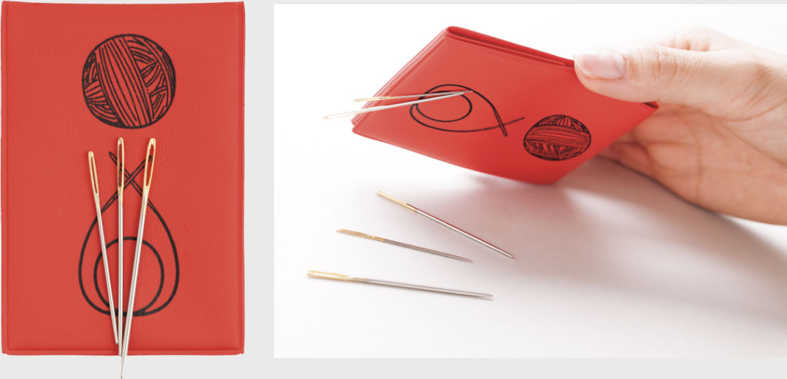 Suporte vermelho para agulhas com estampas a preto e quatro agulhas de metal