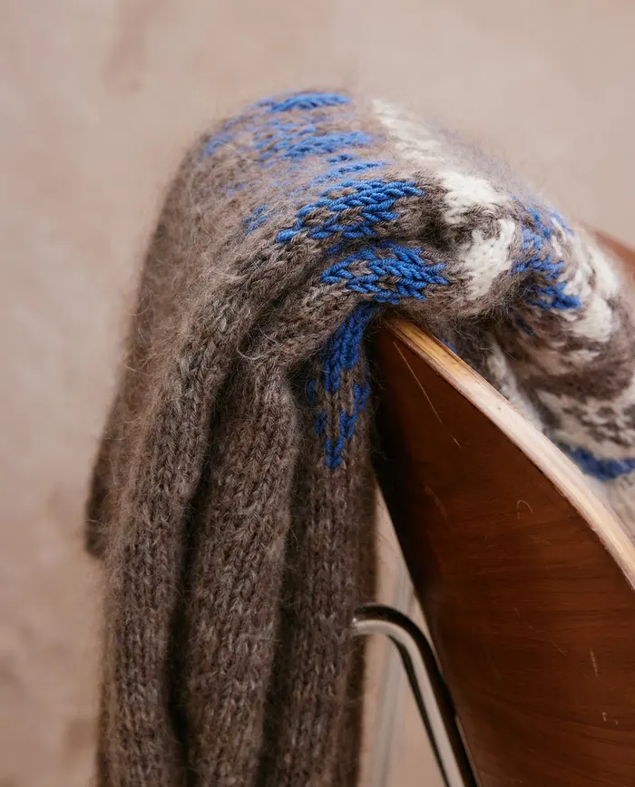 Cachecol de lã mesclada cinza com padrão azul e branco na cadeira