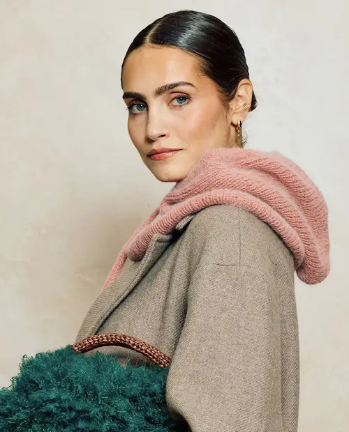 Mulher com casaco bege, cachecol rosa e mala verde de pêlo