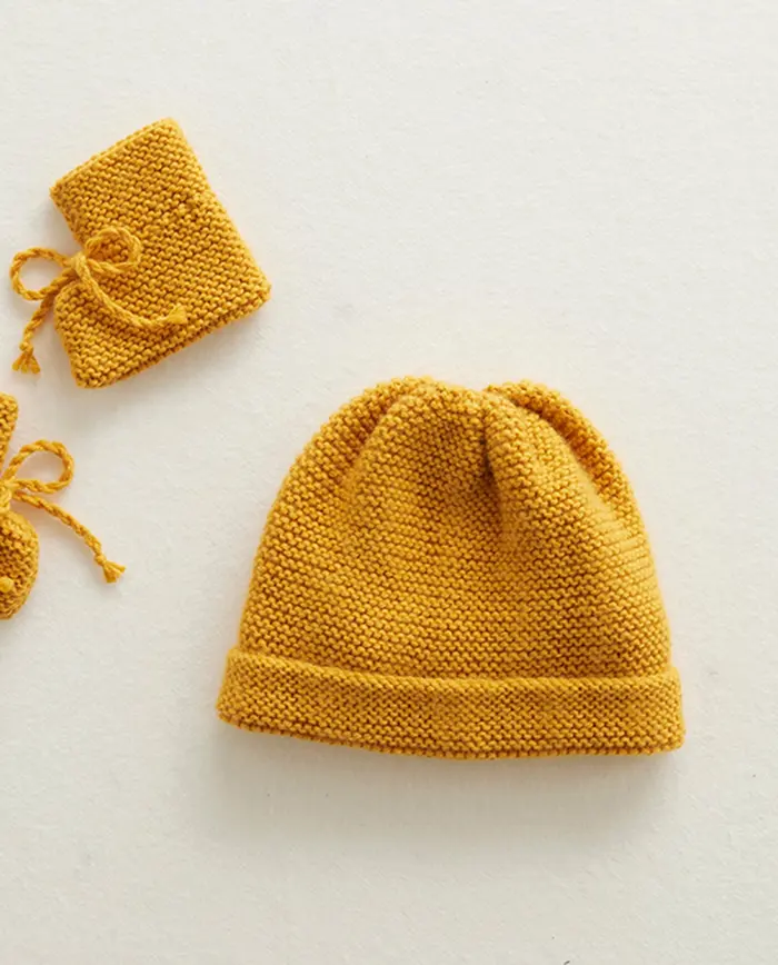Conjunto de gorro e faixa de malha manual mostarda sobre fundo claro