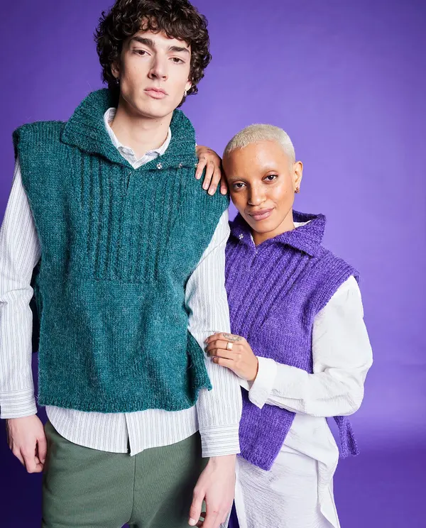 Dois modelos com coletes de malha verde e roxa sobre camisas brancas, fundo roxo.