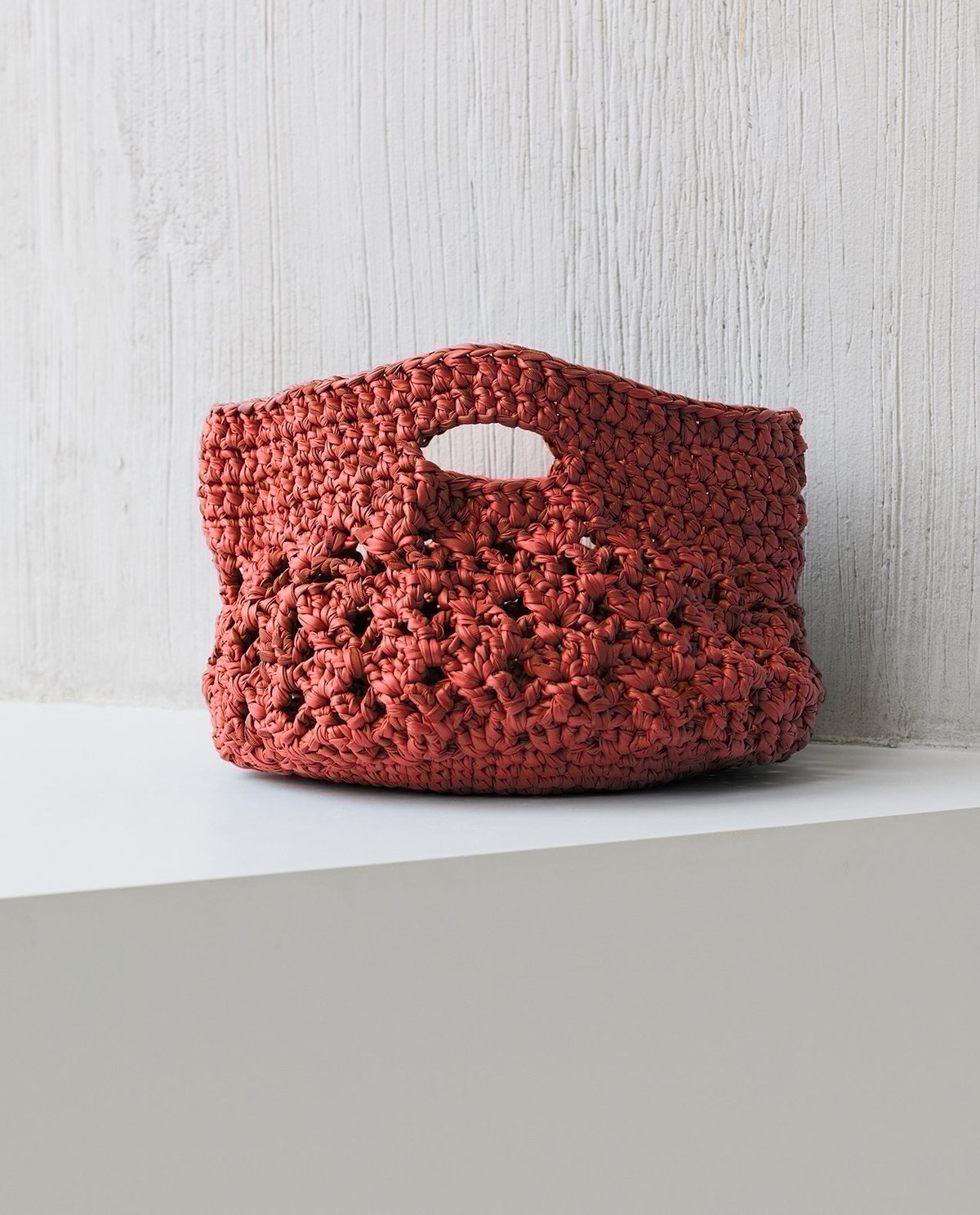 Bolsa de mão de croché terracota com padrão trançado