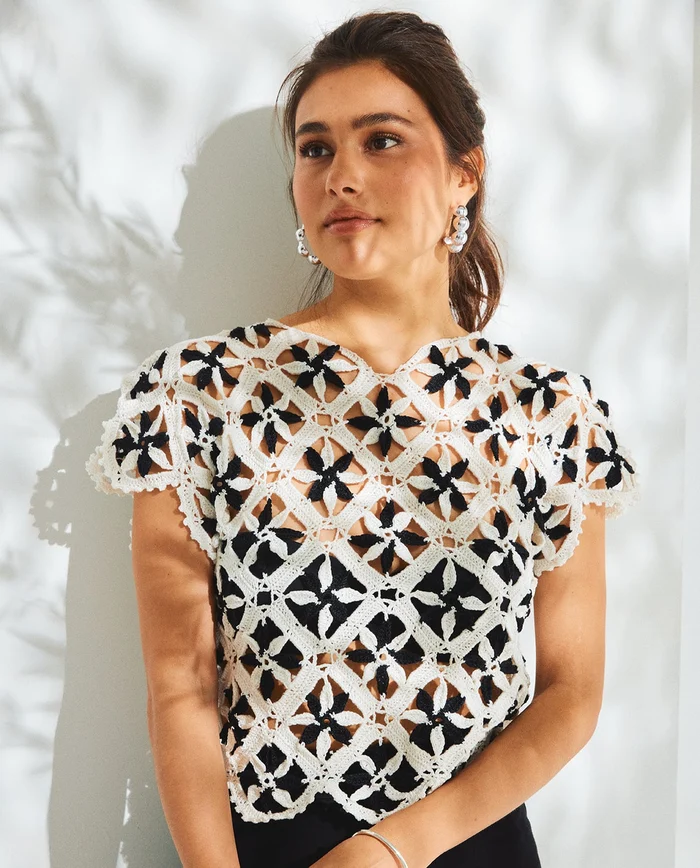 Mulher com camisola de crochet branca e preta com padrões florais