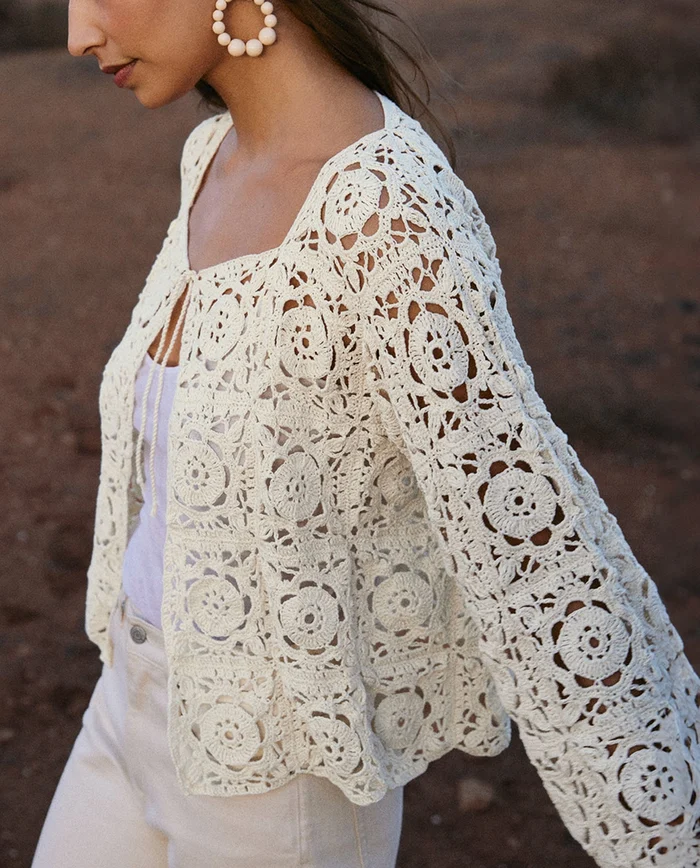 Casaco branco de crochet com padrão floral usado por mulher