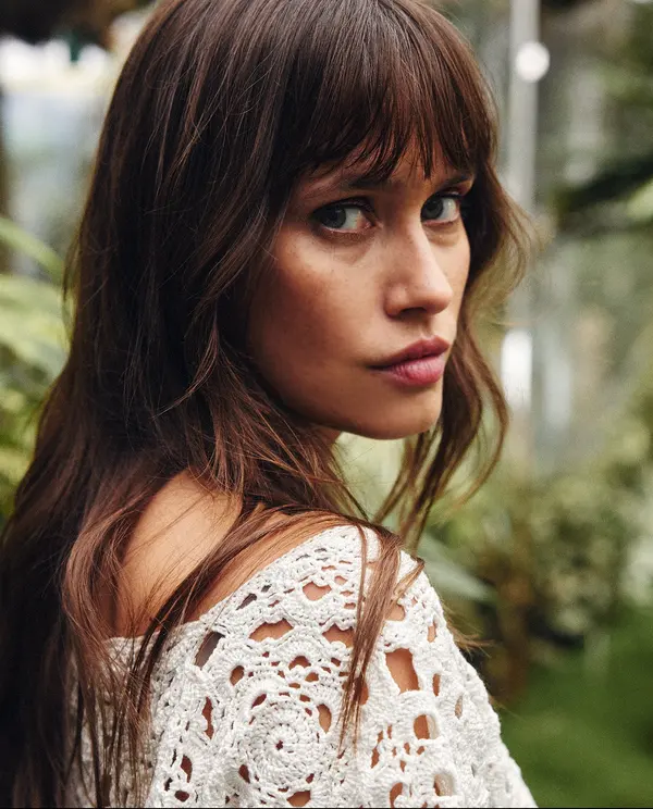 Mulher com top branco de crochet em ambiente exterior verde