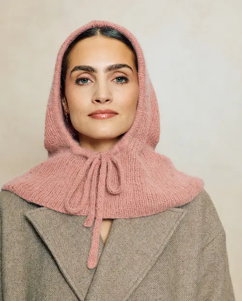 Mulher com capuz rosa de malha e casaco bege