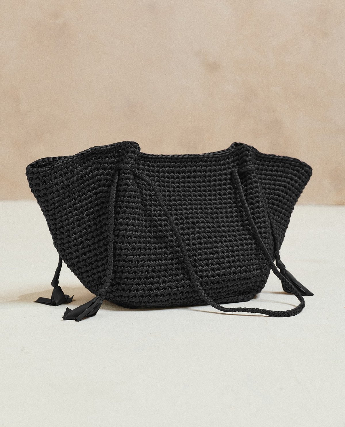 Bolsa preta trançada com alças finas e laços nas pontas