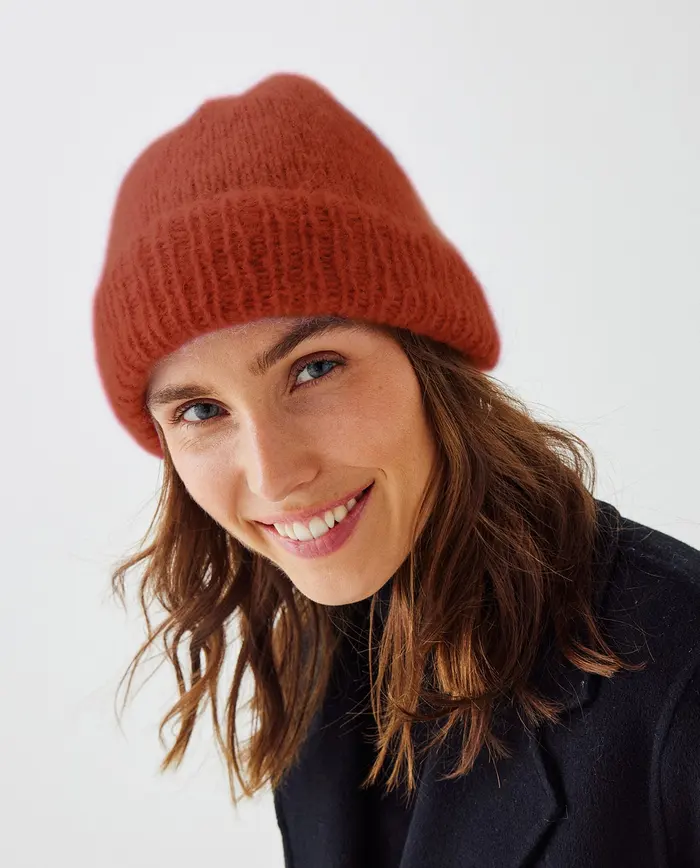 Mulher a usar gorro laranja de malha e casaco preto