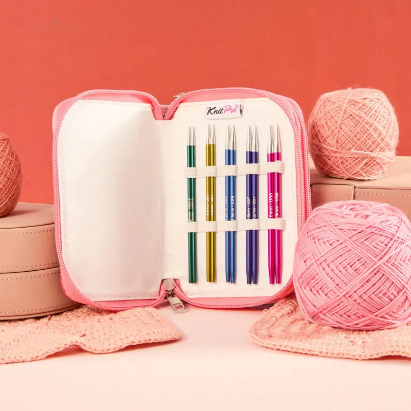 Conjunto de agulhas de tricô metálicas coloridas em bolsa rosa com novelos de lã à volta