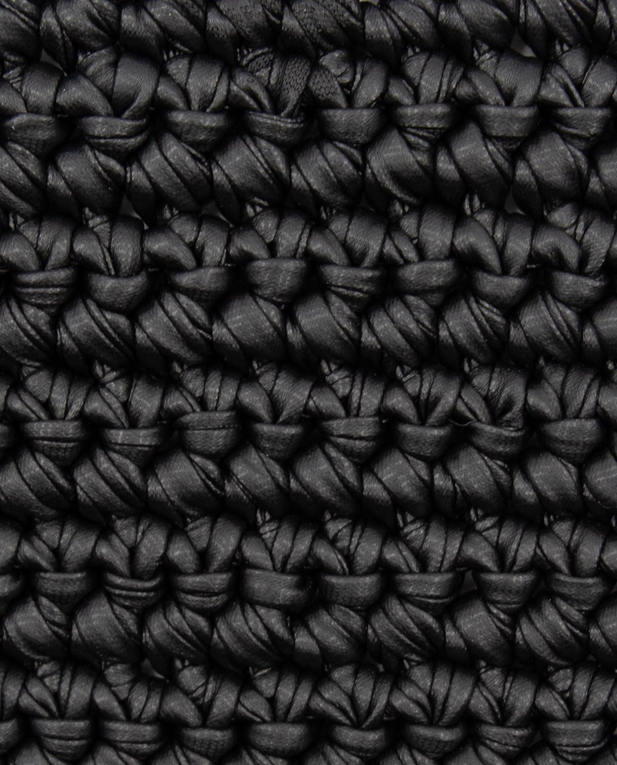 Textura trançada grossa em pano preto com tiras de couro.