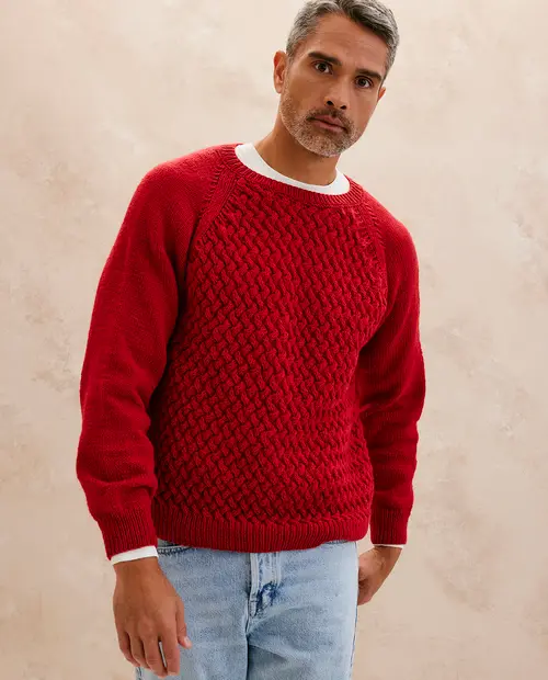 Homem a usar camisola vermelha de malha trançada com jeans claros