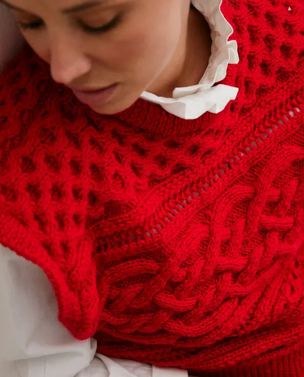 Camisola vermelha de malha com padrão de trança e camisa branca com gola de babados