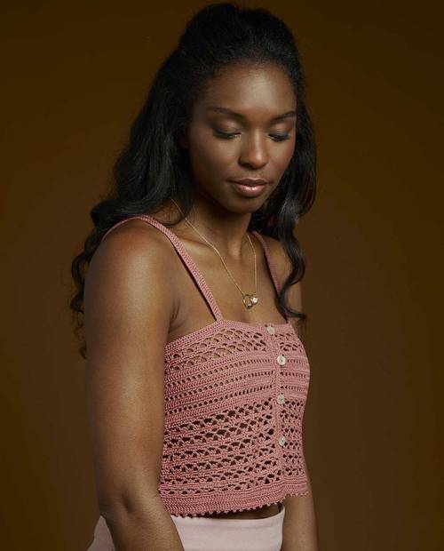 Mulher com top de malha cor-de-rosa com botões frontais e alças finas