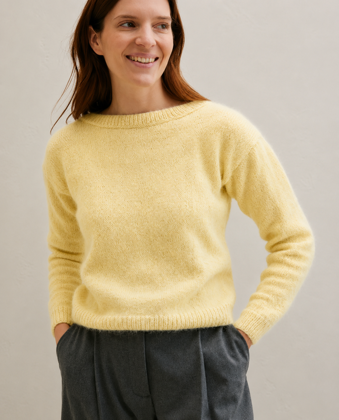 Camisola de malha amarela com calças cinzentas numa modelo sorridente