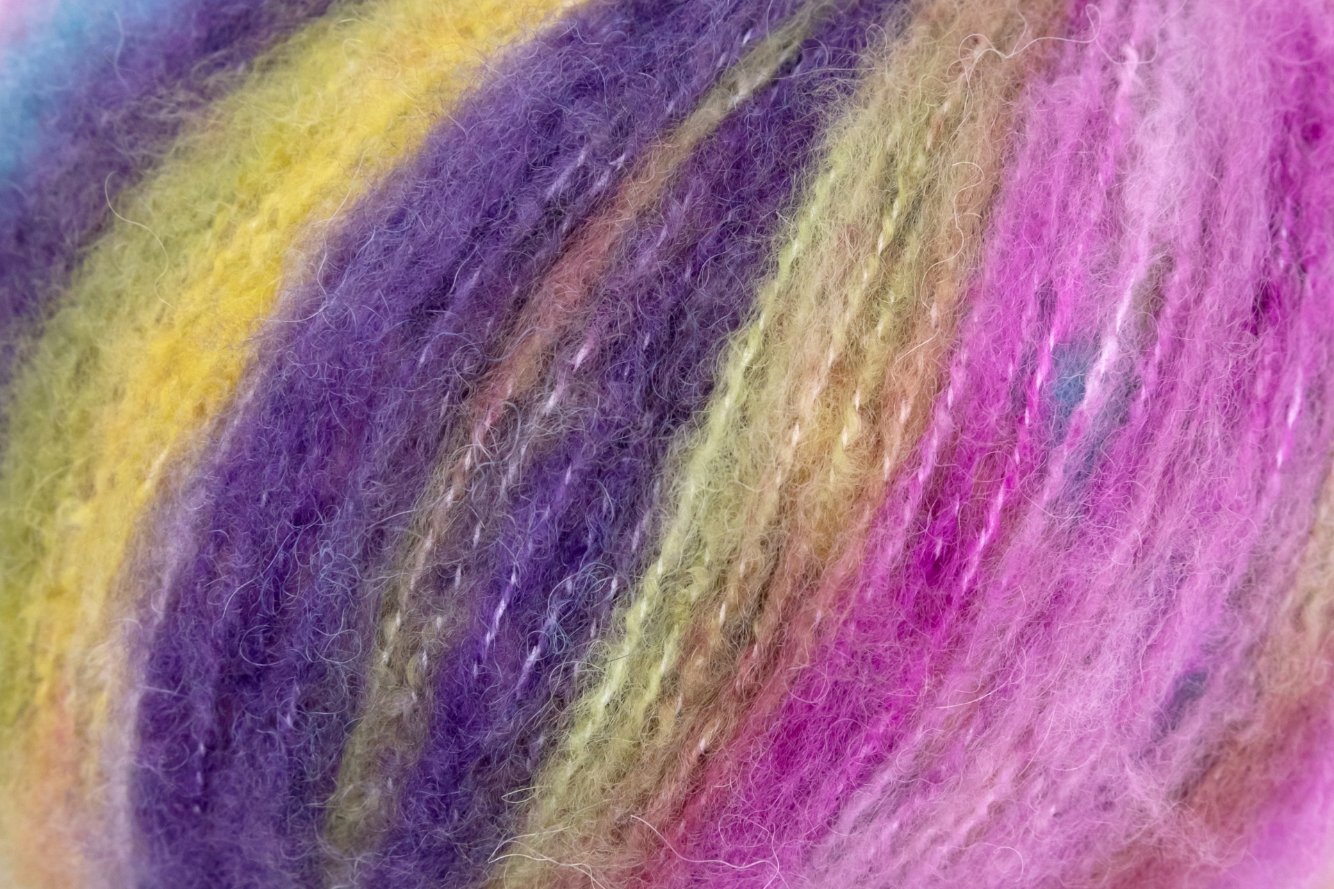 Close-up de novelo colorido de fio felpudo com várias cores como amarelo e lilás