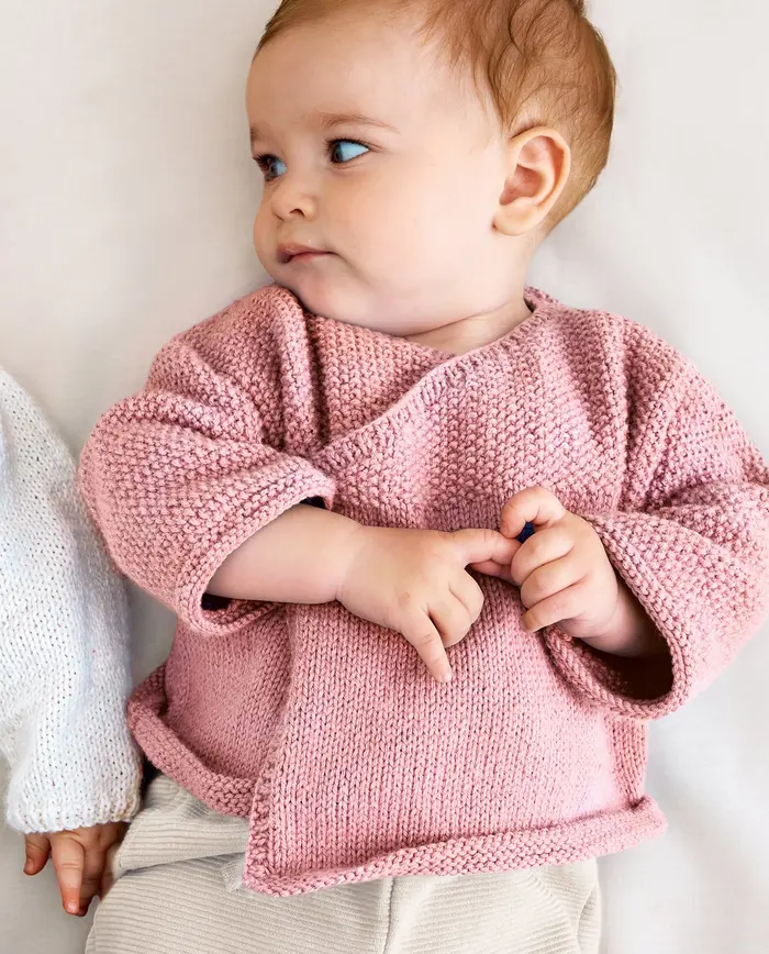 Bebé com camisola rosa de malha sentada