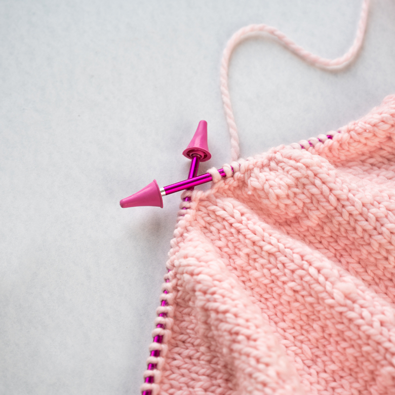 Projeto de malha rosa claro com agulhas de tricô roxas com pontas rosas
