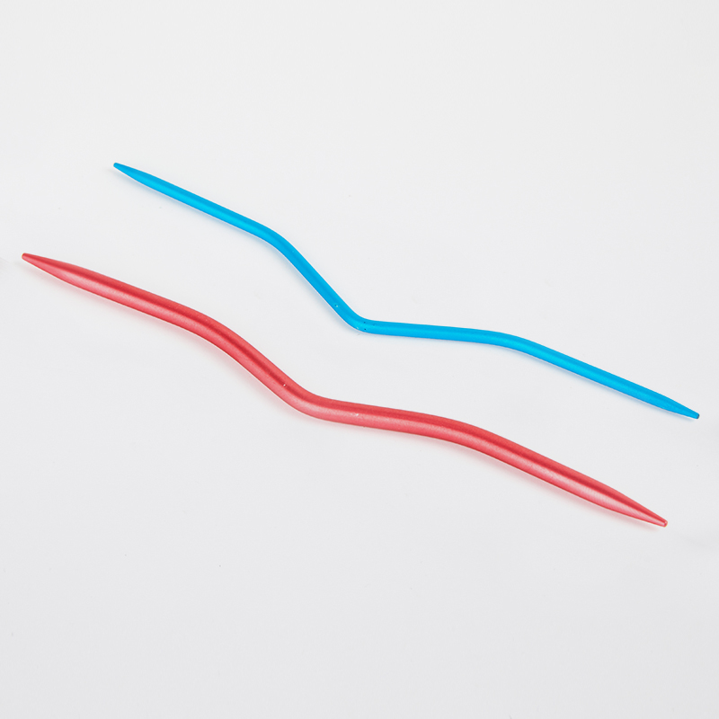 Duas agulhas de tricô plásticas, azul e vermelha, em superfície branca
