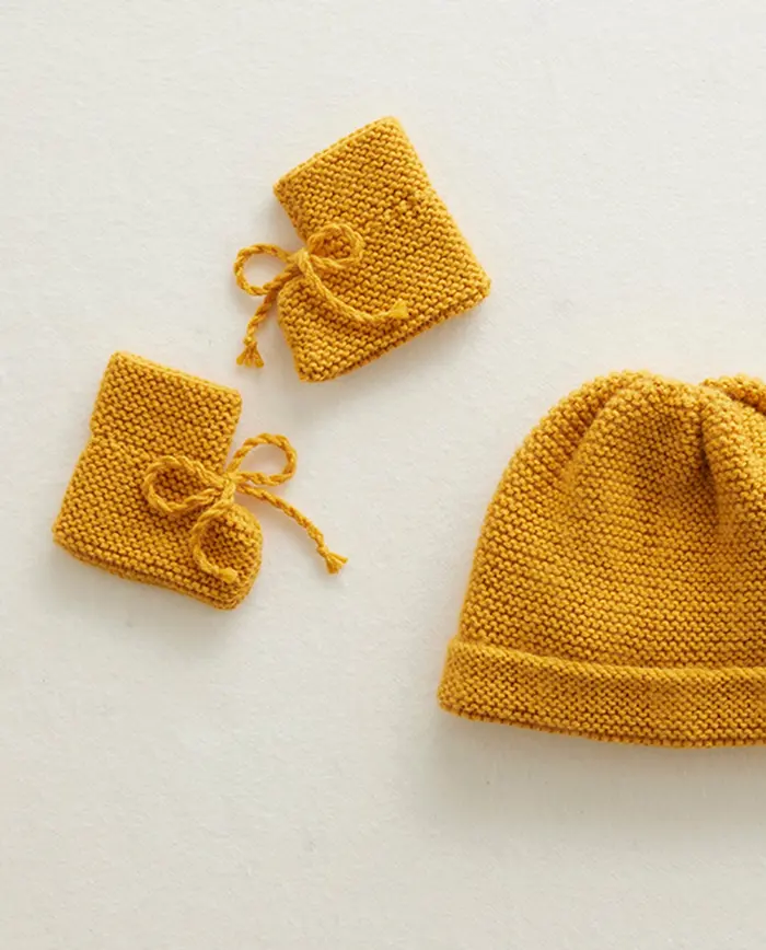 Gorro e luvas de malha mostarda com textura espessa e laços nas luvas