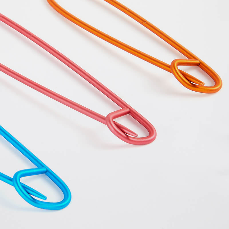 Três cabides de metal coloridos em azul, vermelho e laranja sobre fundo branco