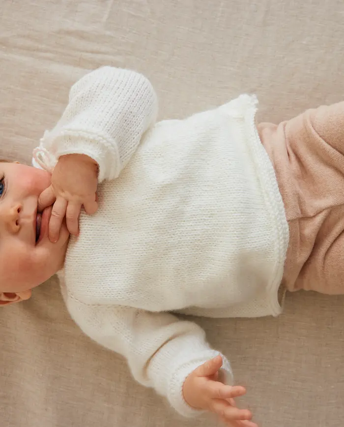 Bebé com camisola branca e calças cor de rosa deitado