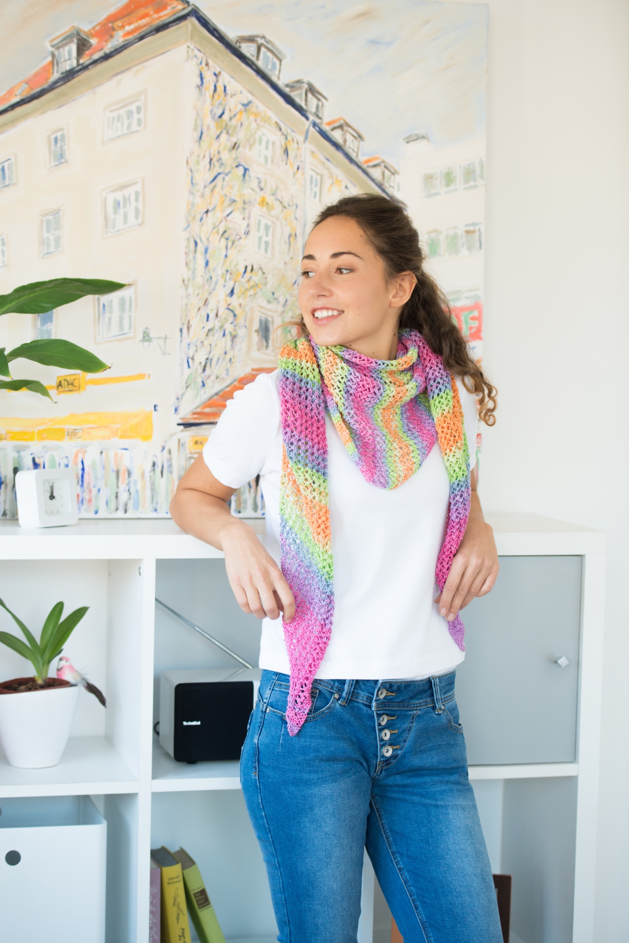 Lenço colorido em malha usado por jovem junto a estante branca