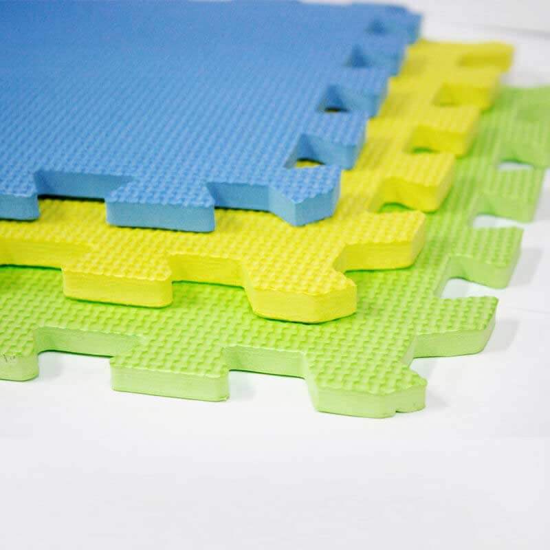 Três peças de tapete tipo puzzle em verde, amarelo e azul com textura antiderrapante.