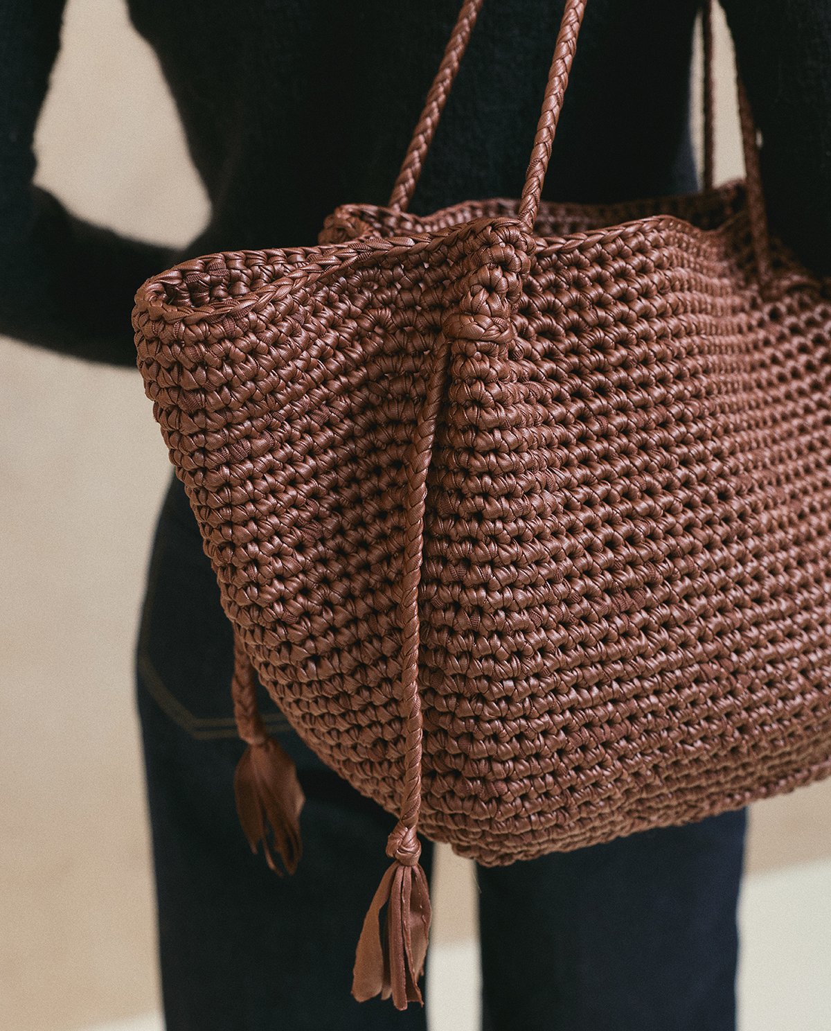 Mala castanha trançada com franjas e alças, usada ao ombro.