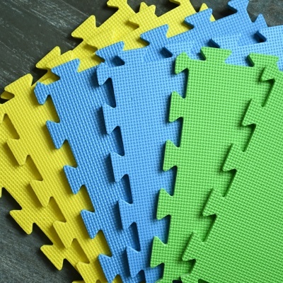 Tapetes de espuma EVA em amarelo, azul e verde com padrão de grades, sobre superfície escura