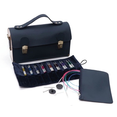 Bolsa preta de couro com fivelas douradas, canetas coloridas e estojos em veludo azul