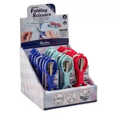 Tesouras compactas dobráveis a azul, verde e vermelho numa caixa de exposição