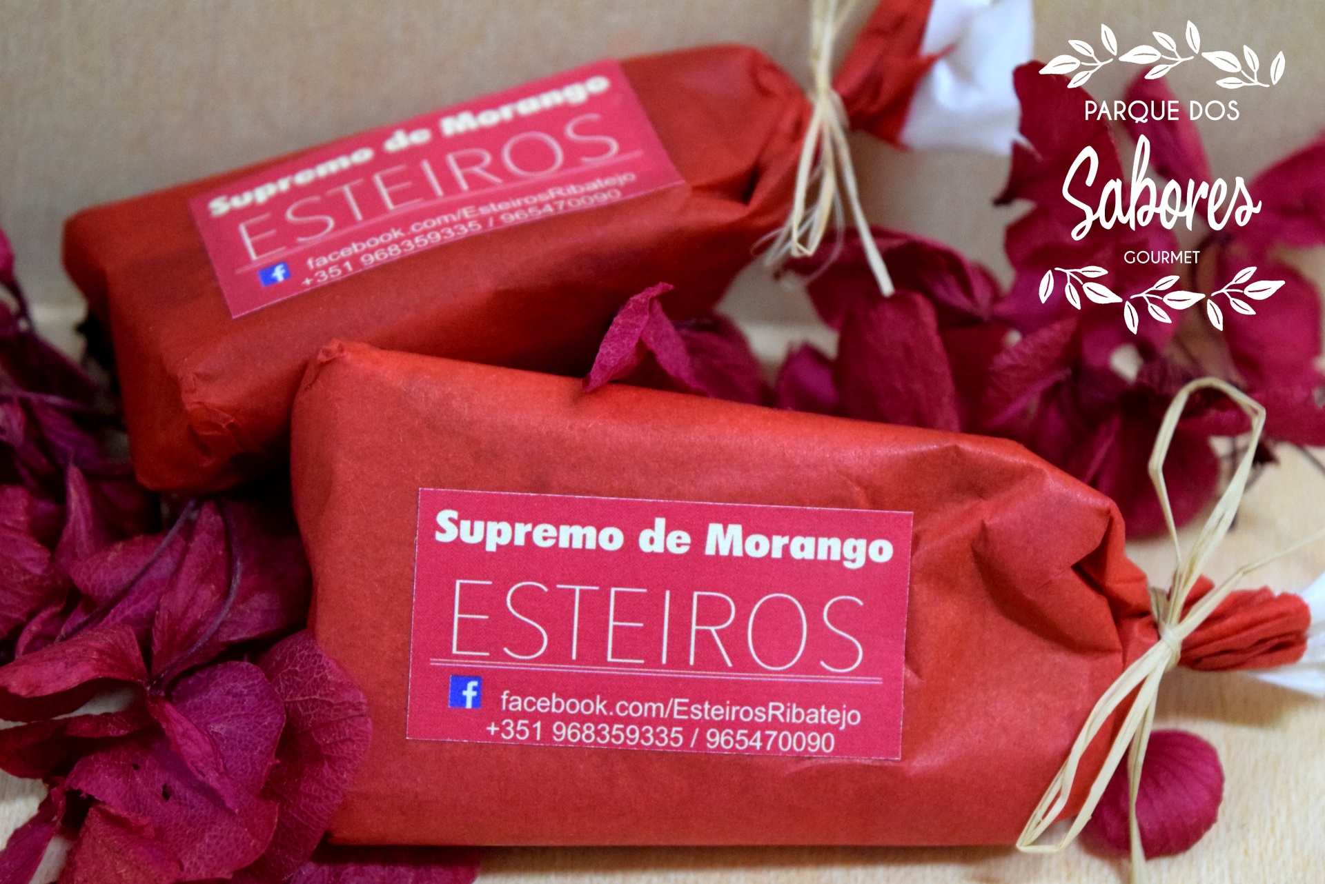 Três produtos embrulhados em papel vermelho com etiqueta 'Supremo de Morango ESTEIROS' e folhas decorativas vermelhas