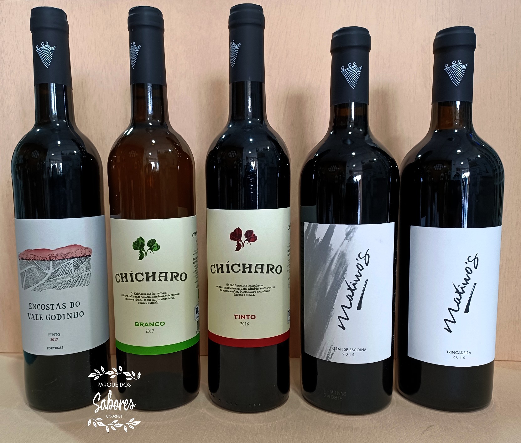 Cinco garrafas de vinho com diferentes etiquetas alinhadas em fila.