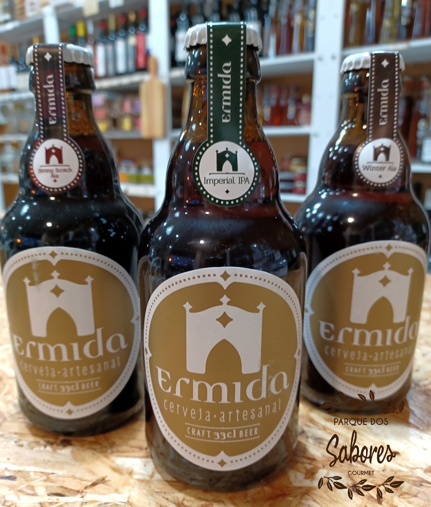 Três garrafas de cerveja artesanal Ermida com rótulos castanhos e bege