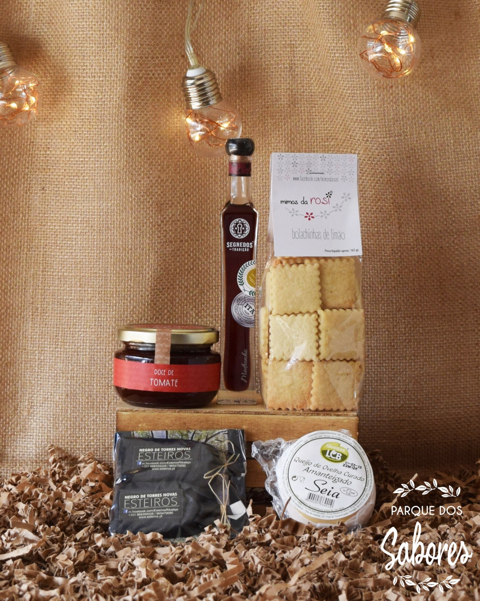 Produtos alimentares compostos por doce de tomate, licor, massa e queijos sobre fundo castanho com luzes decorativas