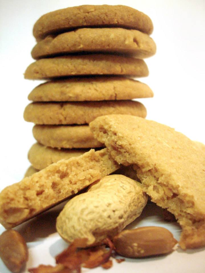 Bolachas douradas empilhadas com amendoins em fundo branco