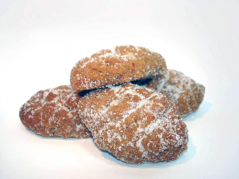 Quatro biscoitos amarelo-dourados cobertos com açúcar, em fundo branco